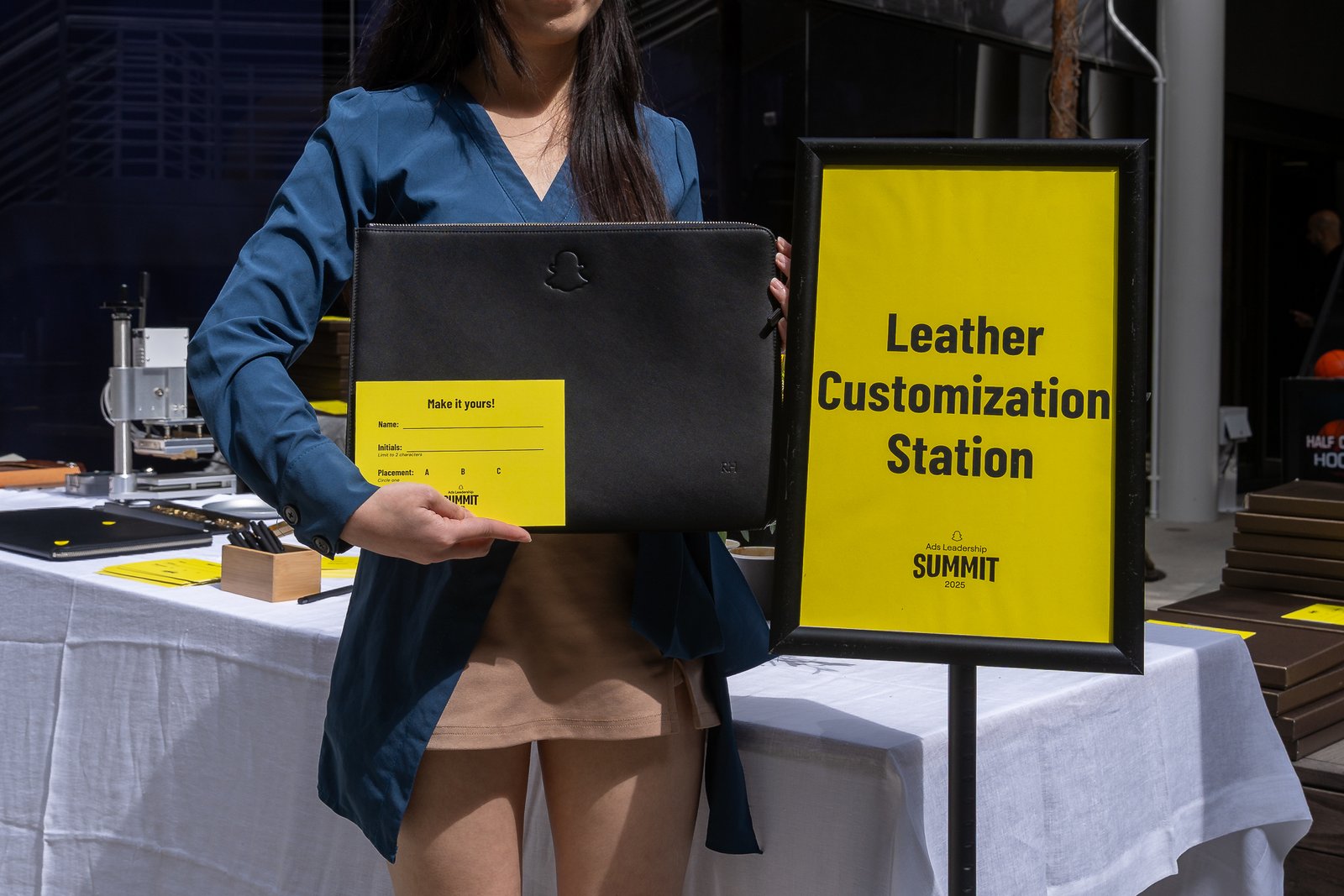 Guest holding personalized onsite embossed leather laptop case at Snapchat Leadership Summit, showcasing unique event activation with monogram and custom embossing.