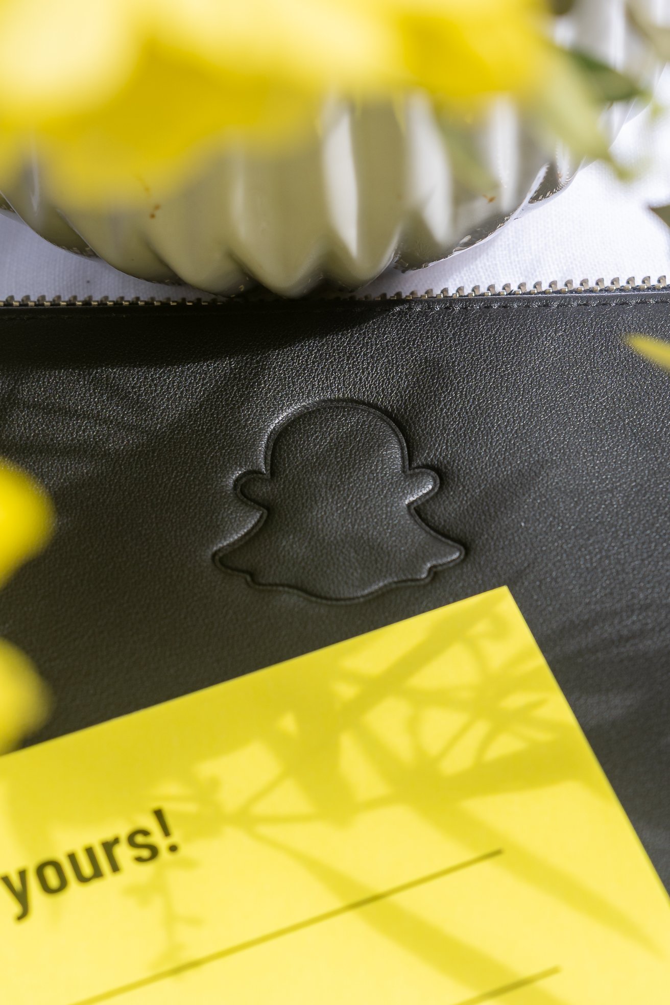 Close-up of custom embossed Snapchat logo on leather item with bright yellow card, part of onsite activation at 2025 Snapchat Leadership Summit
