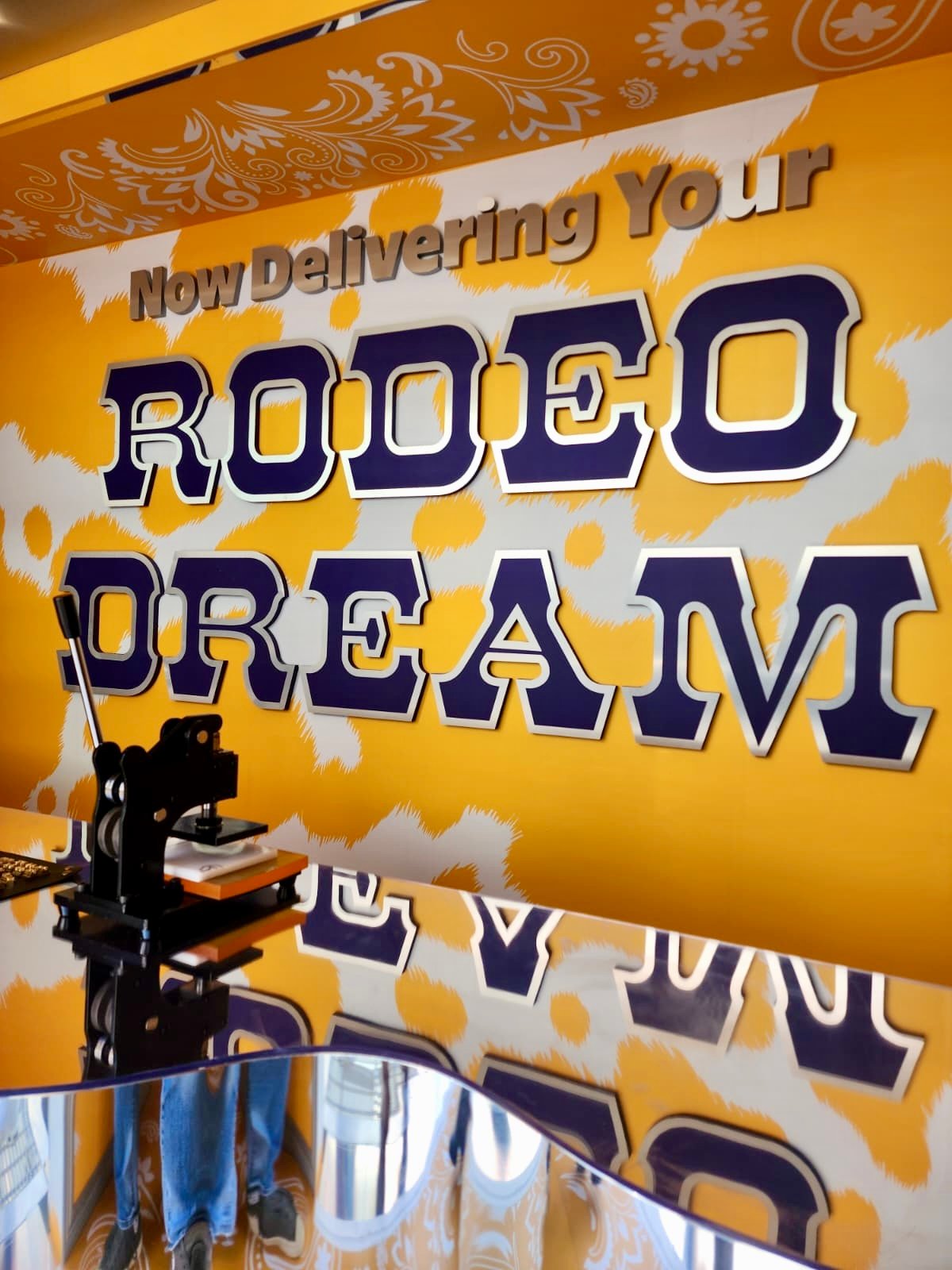 Walmart National Fashion Tour personalization station – western belts embossed with initials and rivet decorations under “Now Delivering Your Rodeo Dream” backdrop