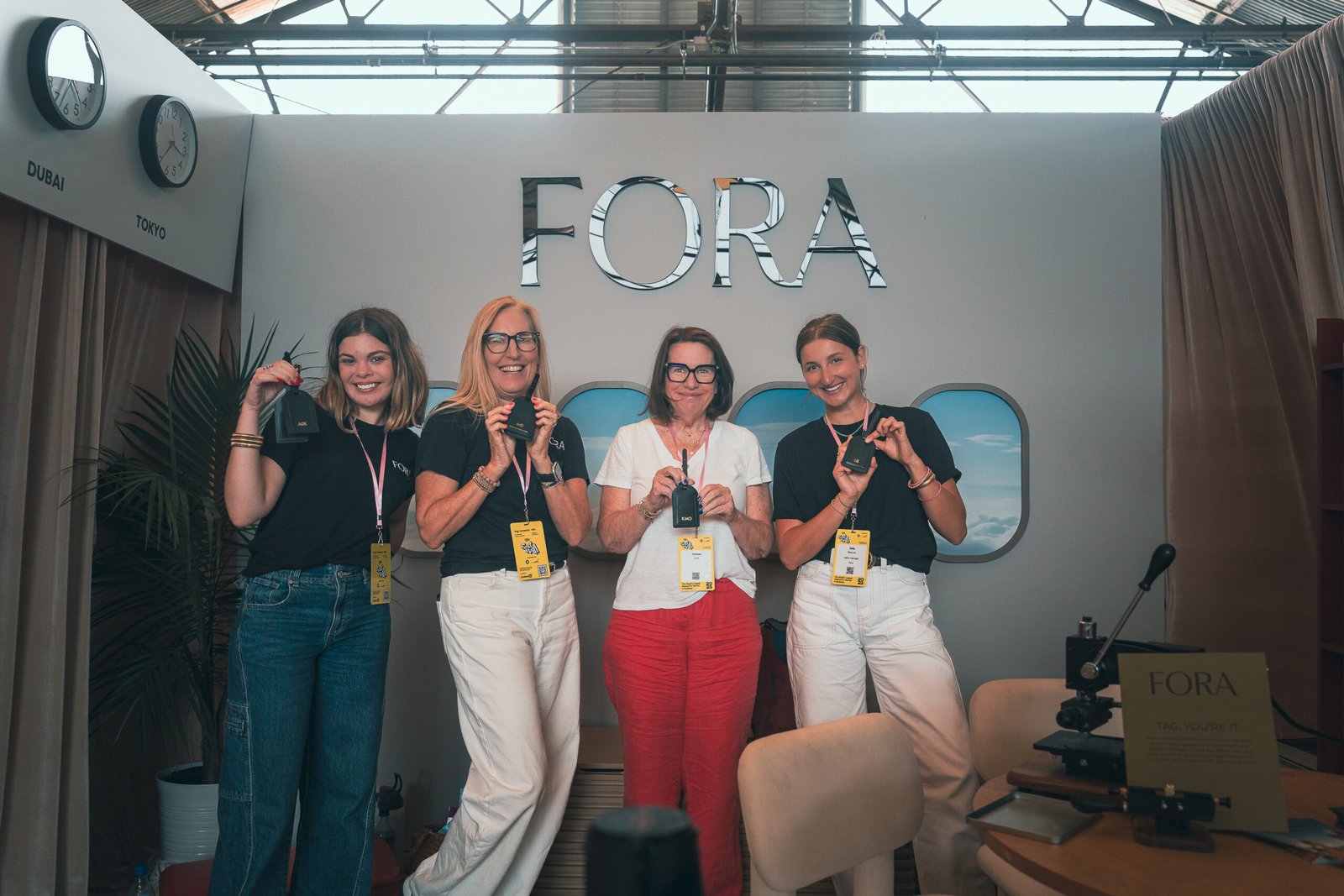 Fora_Travel_Onsite_Embossing_Luggage_Tags_Create_Cultivate_Festival_2025 Guests smiling and holding personalized leather luggage tags at Fora Travel booth, Create & Cultivate Festival 2025 DTLA