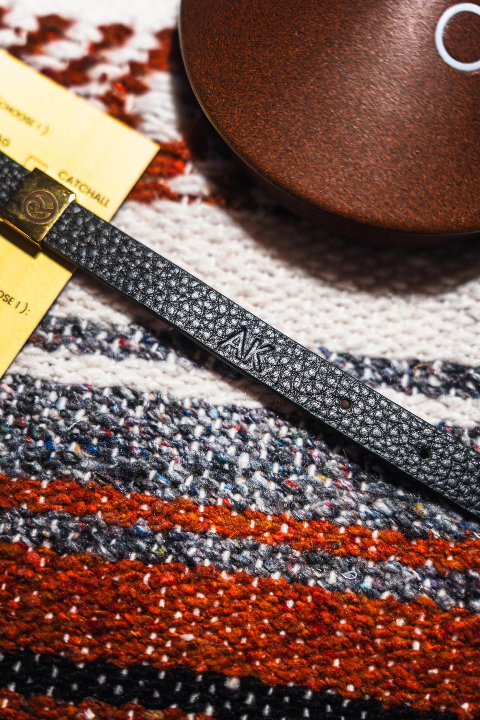 Embossed leather wristband with initials AK, displayed at Rare Beauty’s 5th anniversary, ready for the guest to pick up.