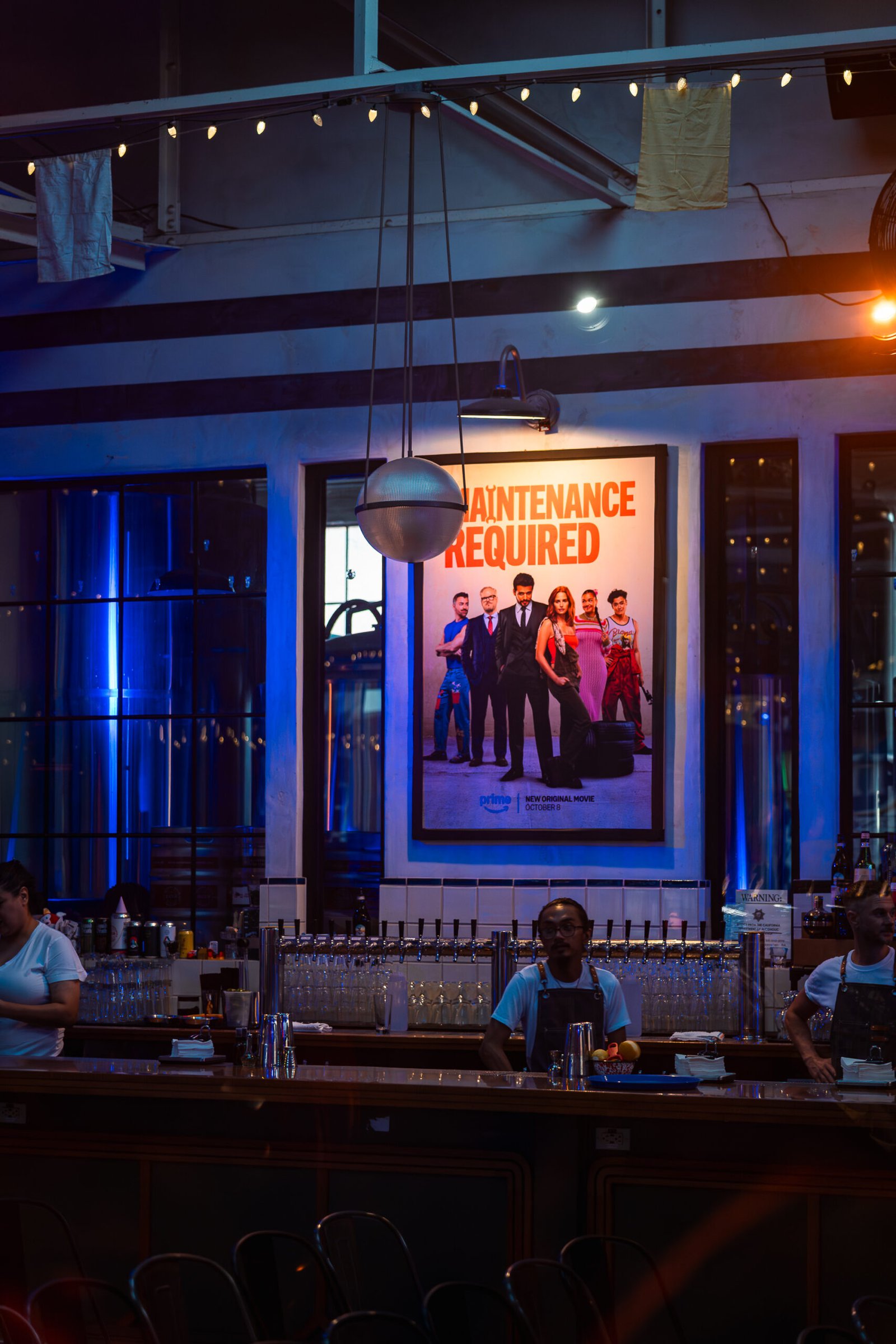 Maintenance_Required_Movie_Poster_At_Retro_Premiere_Venue Maintenance Required movie poster displayed at a retro-style premiere venue for Prime Video’s film event.