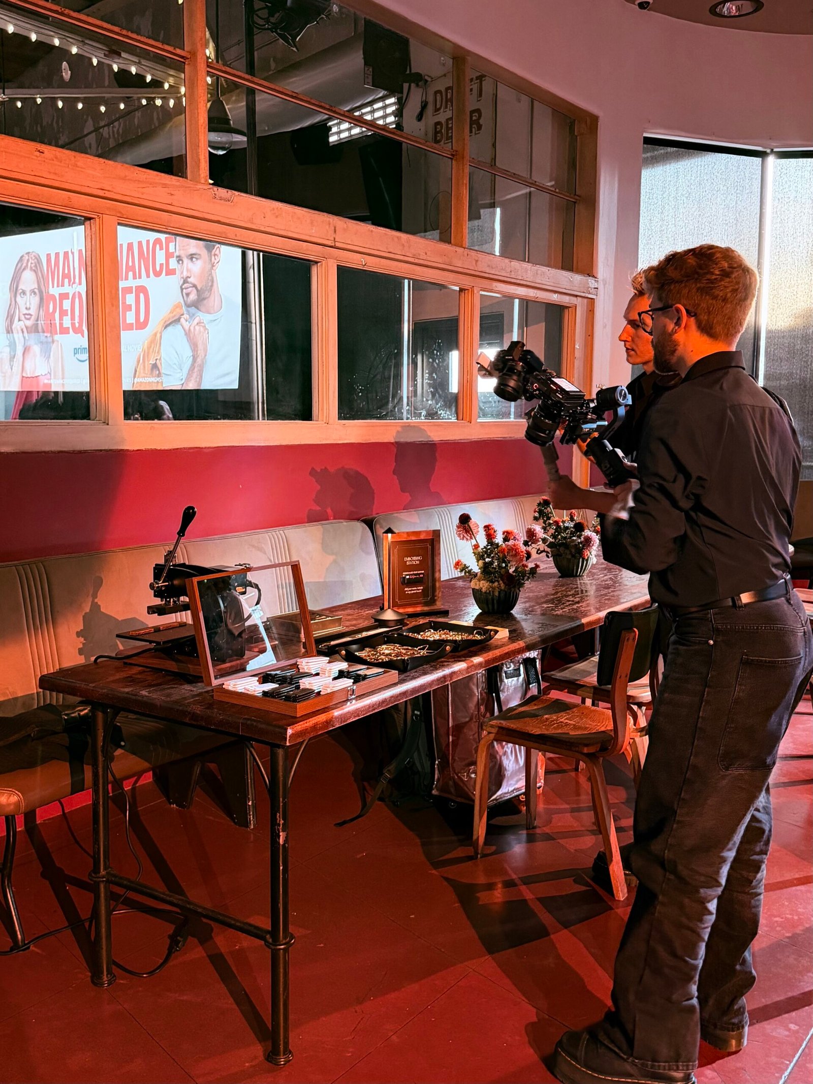 Influencers_Capturing_Embossing_Station_Prime_Video_Maintenance_Required Two influencers capturing photos and videos of the onsite embossing station at Prime Video’s Maintenance Required premiere.