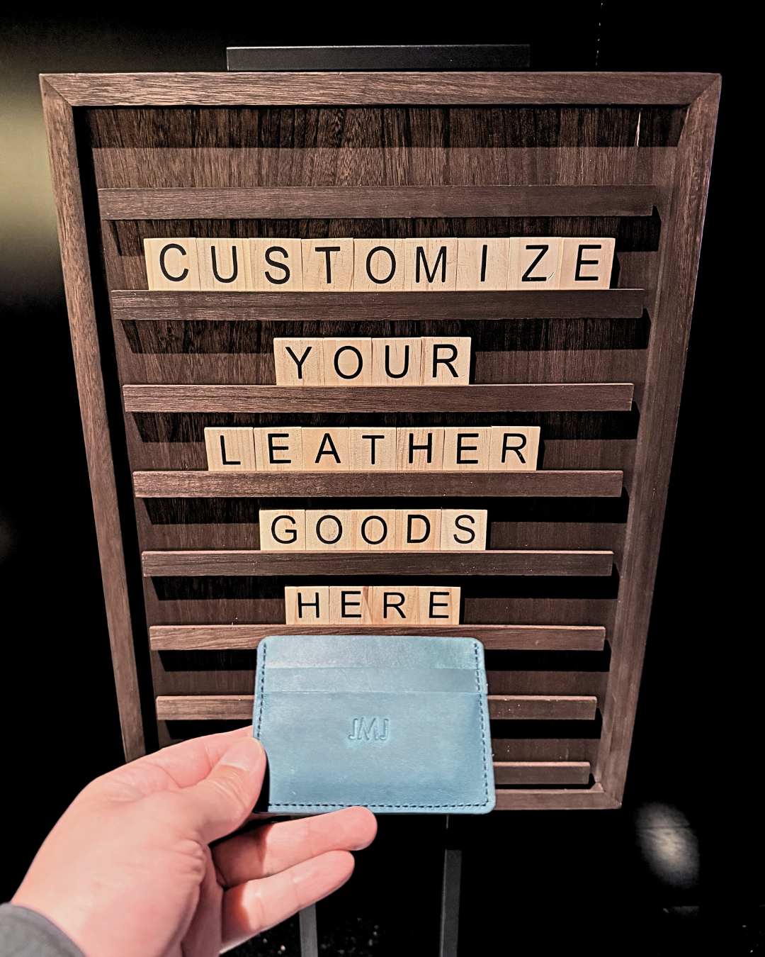 Two white vegan leather license plate keychains from Prime Video’s Maintenance Required premiere, one embossed with KU in dark blue foil and the other showing the debossed “Maintenance Required” and “Prime Video” logos.