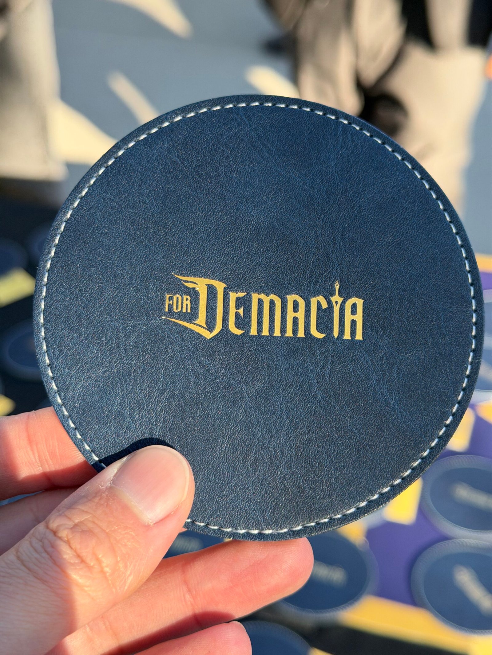 Two white vegan leather license plate keychains from Prime Video’s Maintenance Required premiere, one embossed with KU in dark blue foil and the other showing the debossed “Maintenance Required” and “Prime Video” logos.